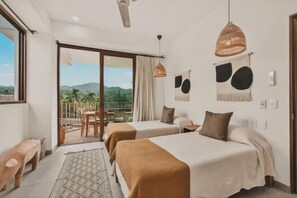 Een hotelkamer met twee bedden, een balkon met uitzicht en een zithoek.
