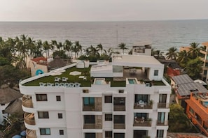 A multi-story hotel with balconies, a rooftop pool, and a view of the ocean. - Mar Azul at La Esquina: San Pancho 2BR Sleeps 6, 1 Block to Beach (San Pancho)