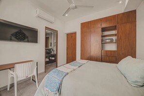 Ein Schlafzimmer mit Bett, Schreibtisch, Stuhl, Kleiderschrank und Deckenventilator.