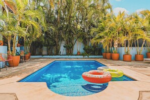 A swimming pool with inflatable rings, surrounded by potted plants and chairs. - Morro Cima Penthouse: Central Sayulita 2BR w/ Terrace, Pool & Ocean Views (Sayulita)