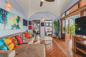 A spacious living area with a sofa, television, and a large painting on the wall. - Morro Cima Penthouse: Central Sayulita 2BR w/ Terrace, Pool & Ocean Views (Sayulita)