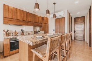 A modern kitchen with wooden cabinets, a granite countertop, and a built-in oven. - Ceiba Tropical at Caivama: Sayulita 2BR, Jungle View & Plunge Pool (Sayulita)