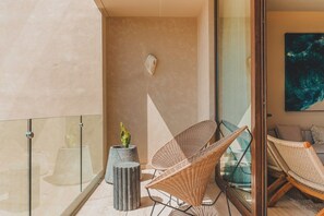 Un interior modern amb un separador de vidre, una planta en test i dues cadires de vimet.