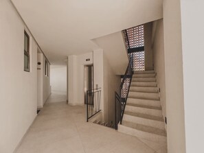 Un couloir avec un escalier menant à un ascenseur.