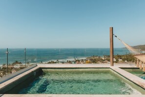 Piscina com água cristalina e vista para o oceano.