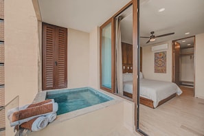 Quarto com cama, piscina pequena e porta deslizante que dá para um banheiro.