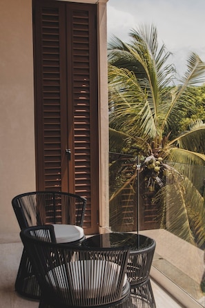 An outdoor seating area with a table and chairs, a wooden door, and a view of palm trees. - Palmera Tropical at Caivama: Sayulita 2BR, Terrace & Plunge Pool (Sayulita)