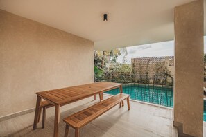 Ein Holztisch und eine Bank auf einem Balkon mit Blick auf einen Pool.