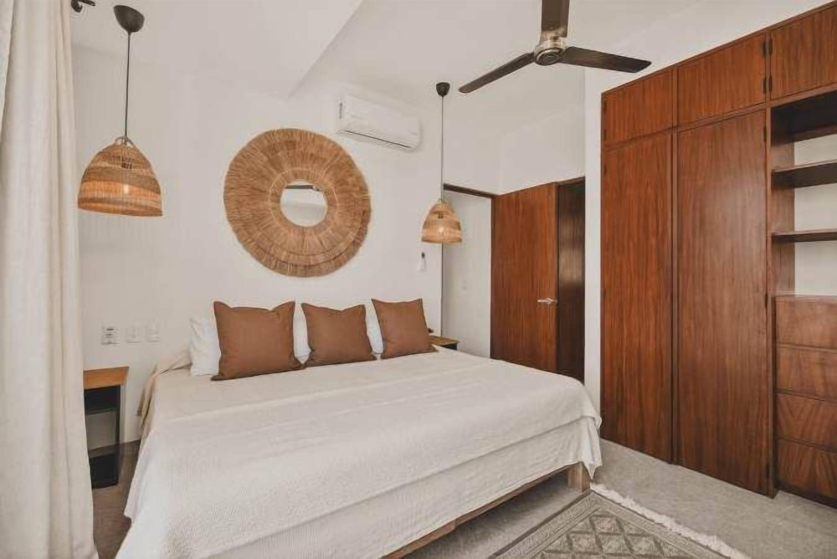 A bedroom with a bed, wooden wardrobe, and a ceiling fan.