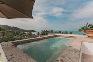 A rectangular swimming pool with a clear view of the ocean and hills in the background. - Vista Verde at La Esquina: San Pancho 2BR, Rooftop Views, 1 Block to Beach (San Pancho)
