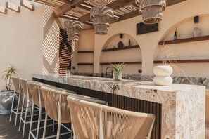 A bar area with a marble countertop, wicker chairs, and pendant lighting. - Vista Magnifico at Caivama: Sayulita 3BR, Plunge Pool & Pacific Views (Sayulita)