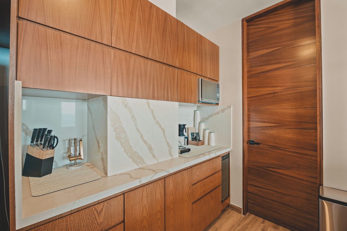 Eine moderne Küche mit Holzschränken, einer Marmorarbeitsplatte und einer eingebauten Mikrowelle.