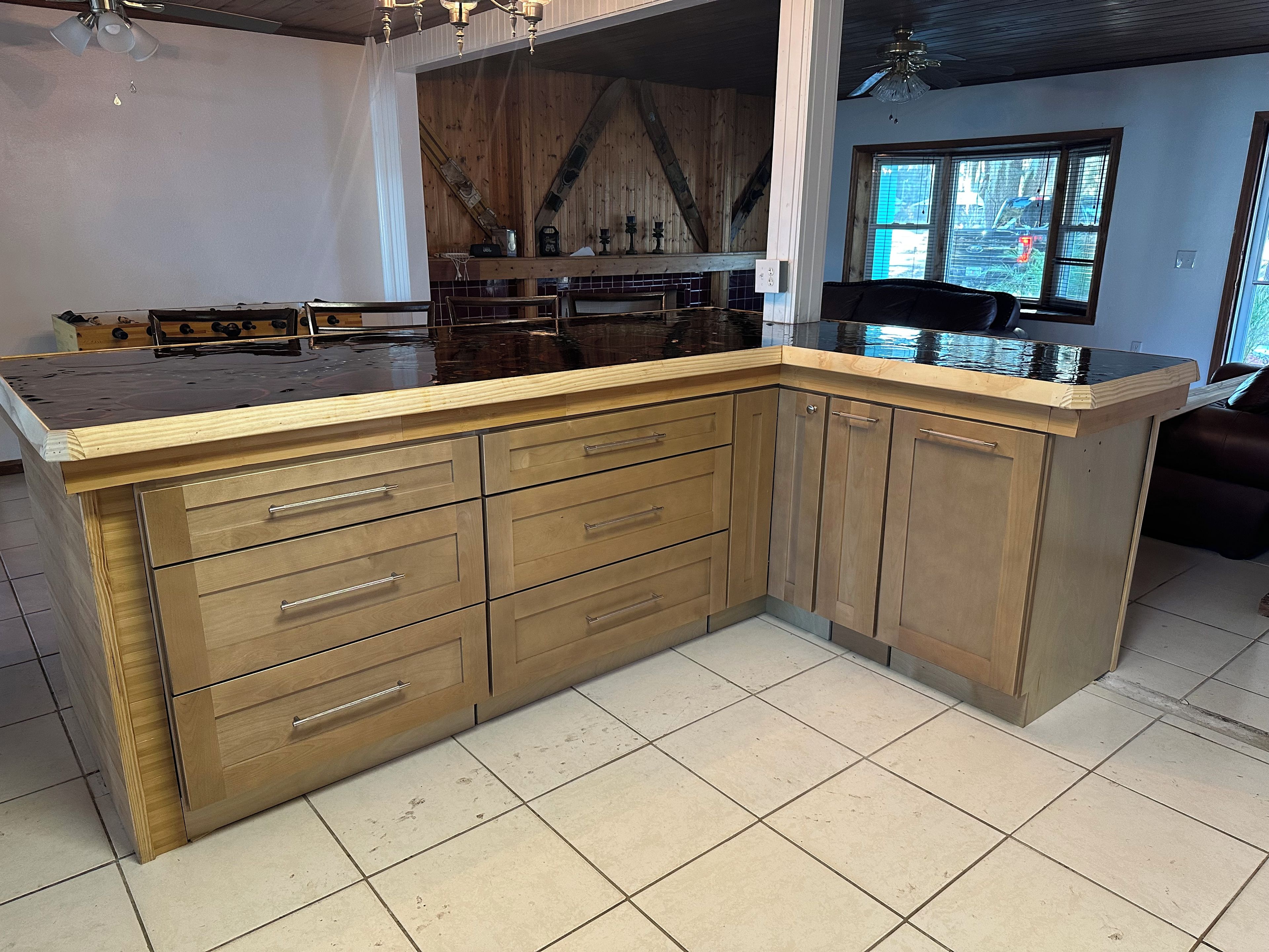 A kitchen with a large island, wooden cabinets, and a tiled floor.