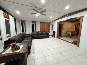 Un salon spacieux avec un canapé d’angle, une table basse et un ventilateur de plafond.