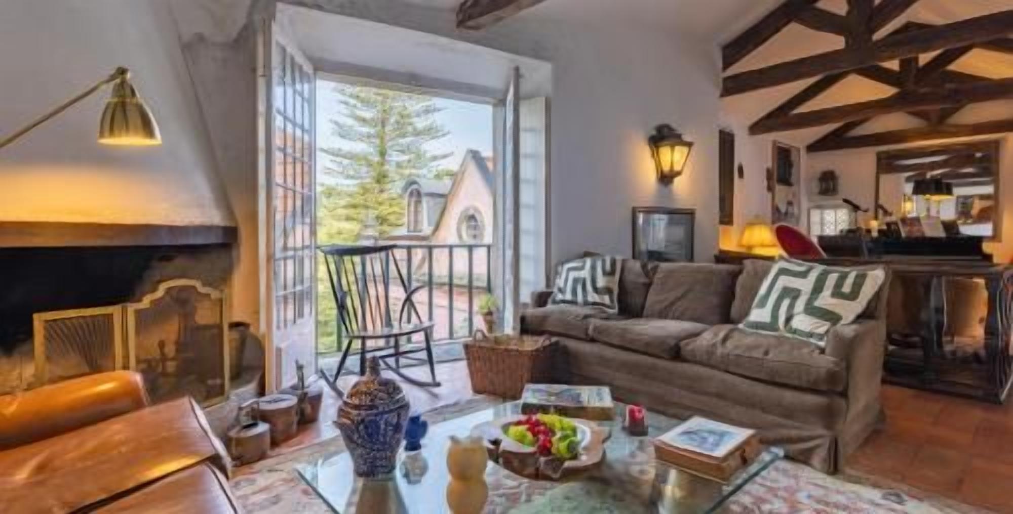 Cozy beamed living room with fireplace and sunny balcony views