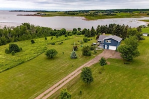 A house with a large lawn, a driveway, and a view of a body of water. - Broadlands Seabreeze Retreat (Nine Mile Creek)