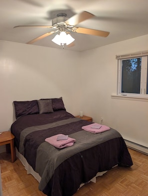 A bedroom with a bed, a ceiling fan, a window, and a nightstand. - Broadlands Seabreeze Retreat (Nine Mile Creek)
