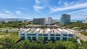 Un hôtel moderne à plusieurs étages, doté de grandes fenêtres et d’une terrasse sur le toit.