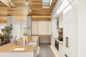 A modern kitchen with a wooden countertop, a sink, and a window with curtains. - Paradise Club by Coast Hosting (Wamberal)