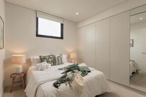 Une chambre à coucher avec un lit, des lampes de chevet, une fenêtre et une armoire.