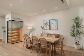 Ein moderner Essbereich mit Holztisch und -stühlen, einer Glastrennwand und zwei gerahmten Bildern an der Wand.