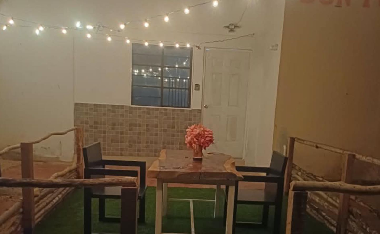 Een kleine kamer met een tafel, stoelen, een raam en een deur.