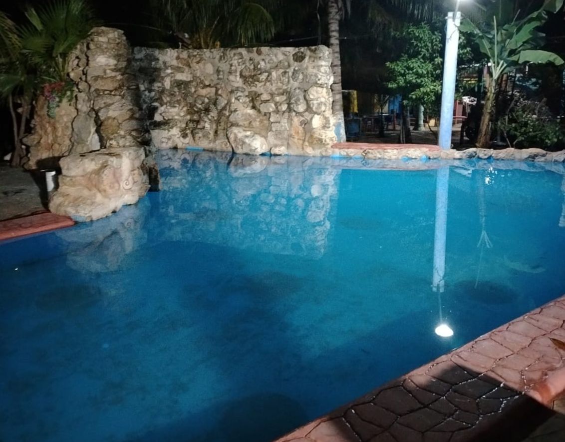 A nighttime swimming pool with stone walls and a tiled edge.
