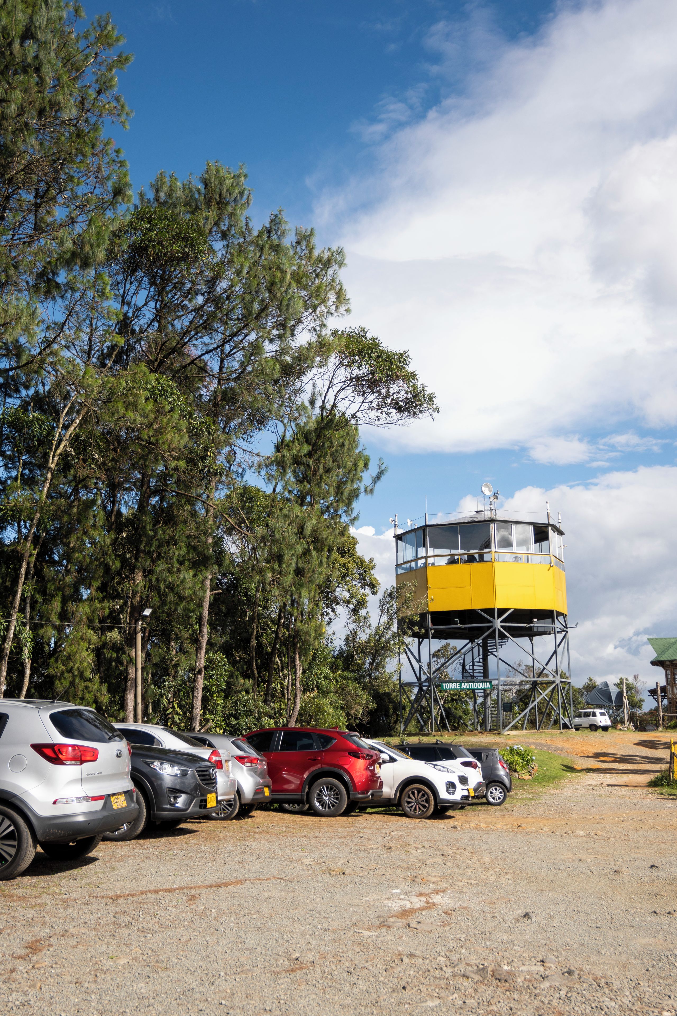 A parking area with several cars and a yellow observation tower.