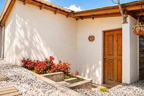 Un edificio con puerta de madera, sendero de piedra y flores rojas.