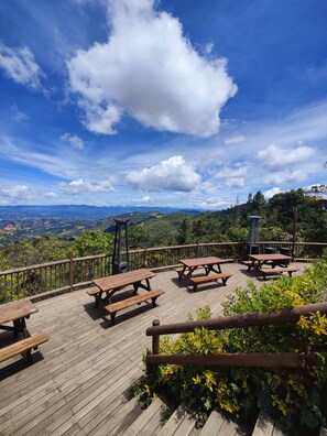 A wooden deck with picnic tables overlooking a mountainous landscape.