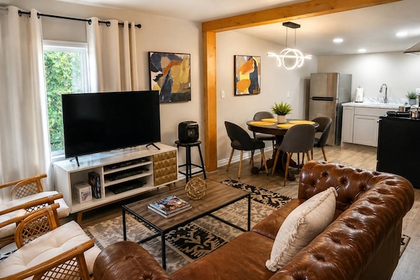 A living room with a TV, sofa, chairs, a coffee table, and artwork on the walls. - 2 Studios + 2BR Home Near Whiskey Row (Prescott)