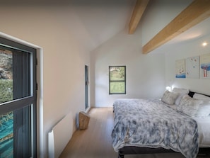 Un dormitorio con cama, ventana y vista al exterior.