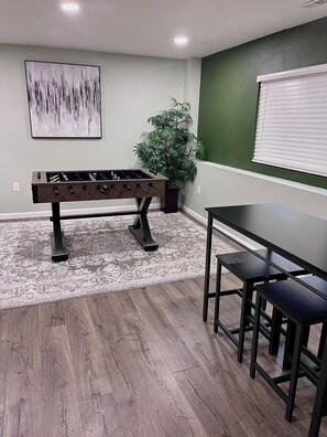 A room with a foosball table, a dining table with chairs, a potted plant, and a painting on the wall. - Whole Black Hawk Home w/ Game Room and Home Gym Near Casinos and Hiking! (Black Hawk)