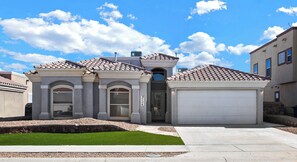 A residential building with a garage, a driveway, and a well-maintained lawn. - Spacious 4BR 3BA 2 masters bedroom  TVs in every room (El Paso)