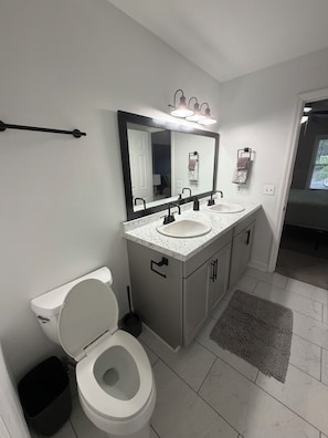 A modern bathroom with a toilet, bidet, and dual sinks with a large mirror above. - Cozy Townhome in the Perfect location! (Columbia)