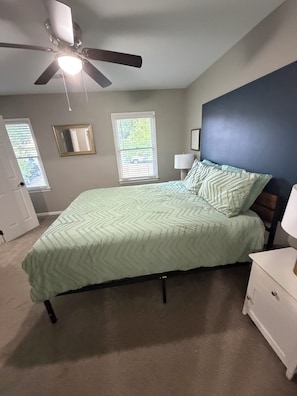 A bedroom with a bed, a ceiling fan, two windows with blinds, a nightstand, and a dresser. - Cozy Townhome in the Perfect location! (Columbia)