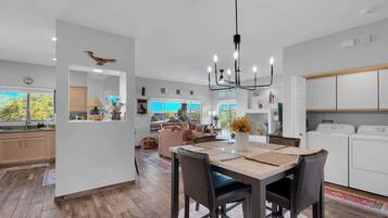 Een moderne keuken met witte kasten, een eethoek met een houten tafel en stoelen, en uitzicht op de omgeving.