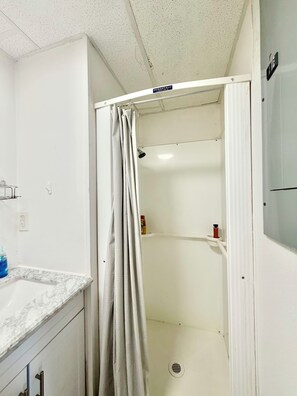 Un bagno con doccia, un piano di lavoro in marmo e un soffitto bianco.