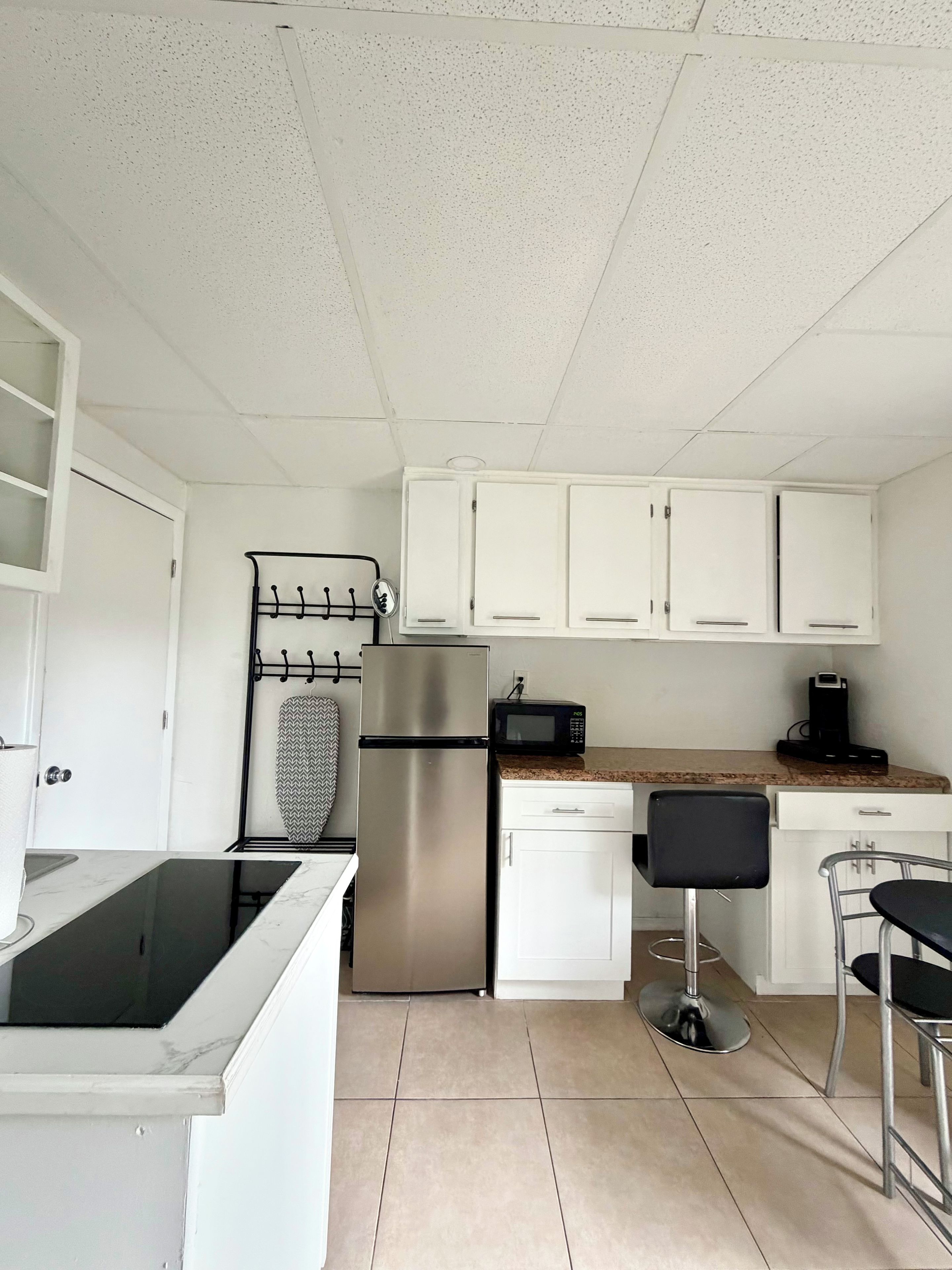 A kitchen with white cabinets, a stainless steel refrigerator, a microwave, and a sink.