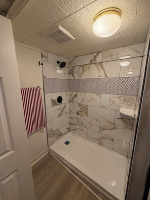 A bathroom with a shower, a toilet, and a towel rack.