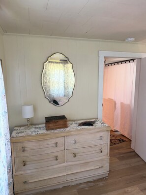 A room with a wooden dresser, a mirror, a lamp, and a door leading to another room. - Reno 3-bed farmhouse with cozy charm in Jonesville’s: local wineries & hiking (Jonesville)