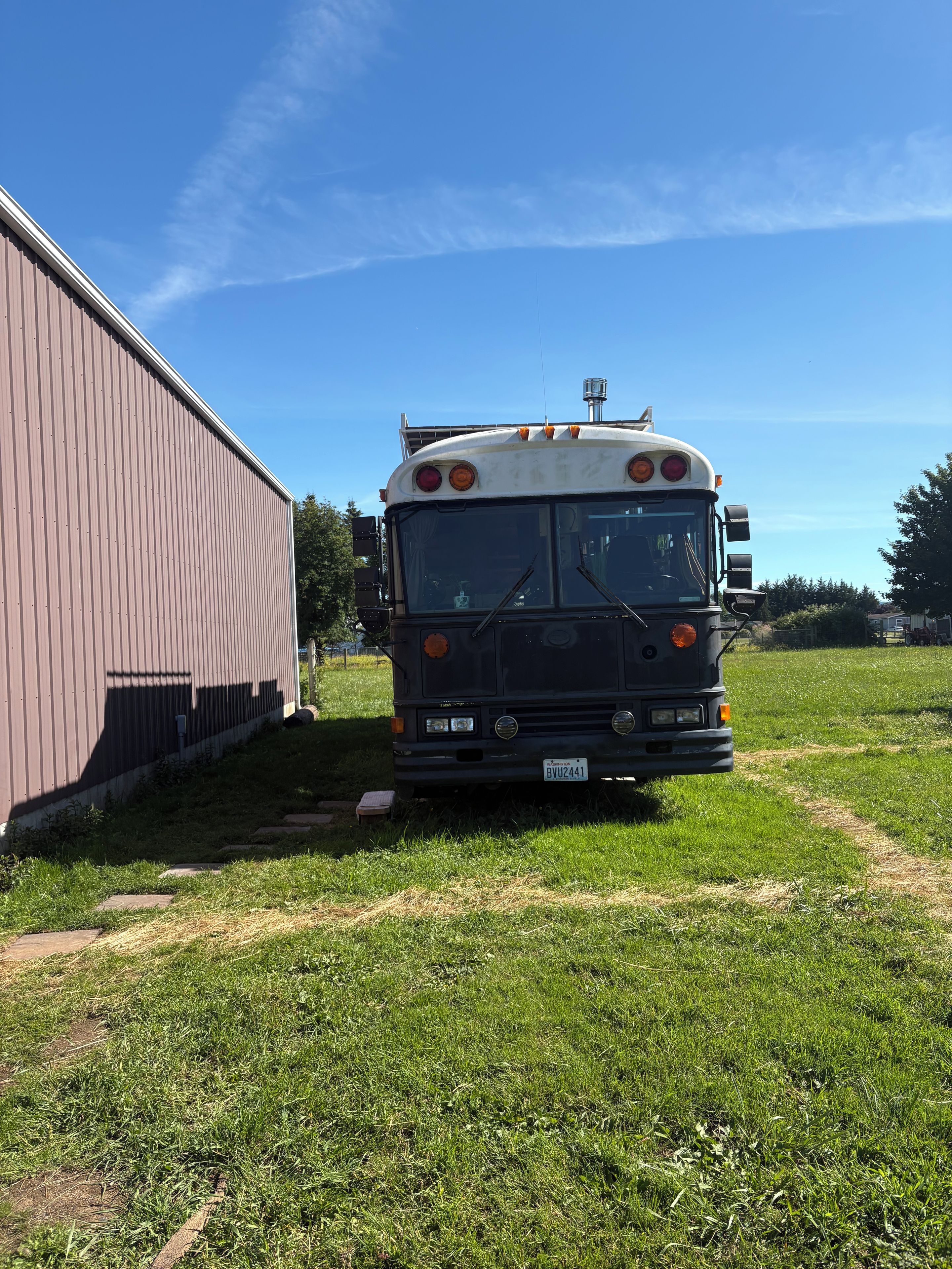 Un autobus est garé dans une zone herbeuse, avec un bâtiment en arrière-plan.
