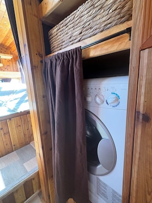 Une buanderie équipée d’un lave-linge, avec des murs en bois et une fenêtre.