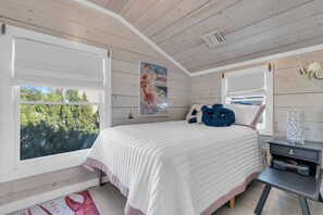 A bedroom with a bed, a nightstand, a lamp, and a poster on the wall. - Shells & Whistle Beach Cottage
Short Walk to SeaWatch Beach Manasquan (Manasquan)