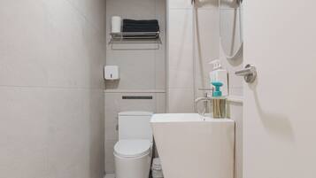 A compact bathroom with a toilet, sink, and shower.