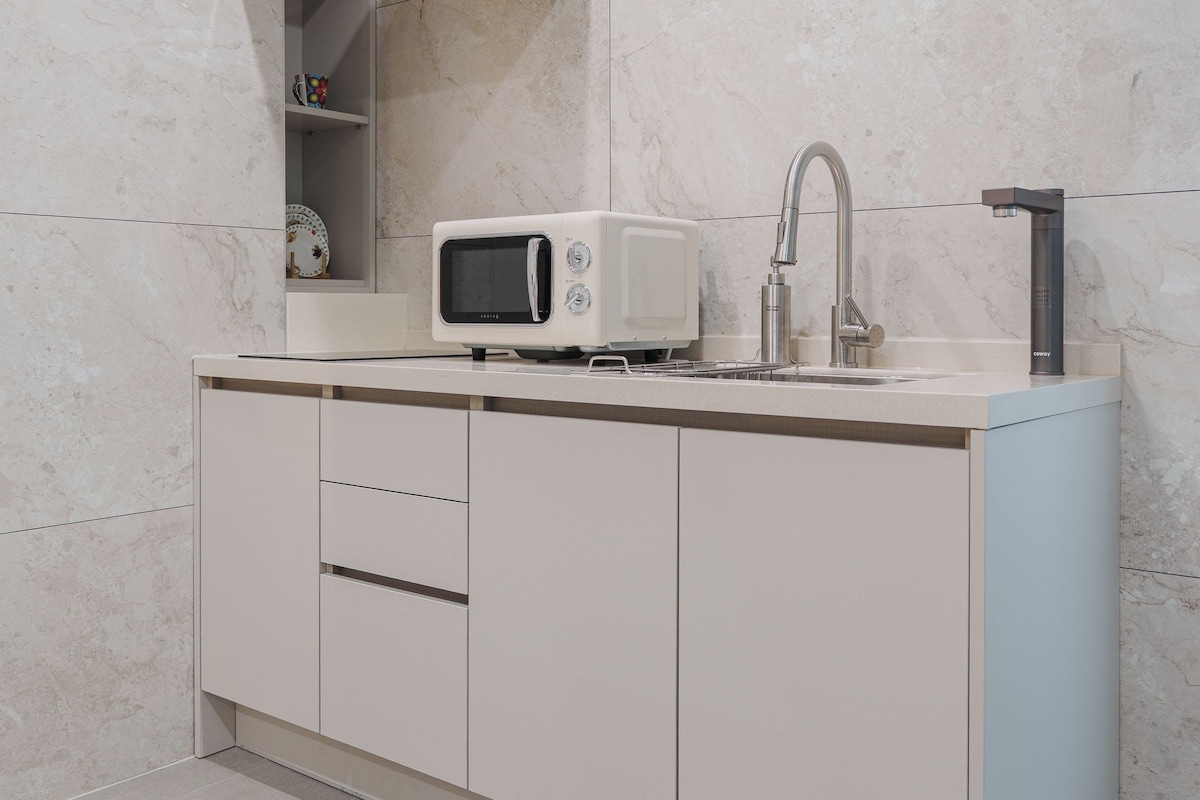 Een moderne keuken met een ingebouwde magnetron, een roestvrijstalen spoelbak en een afzuigkap.