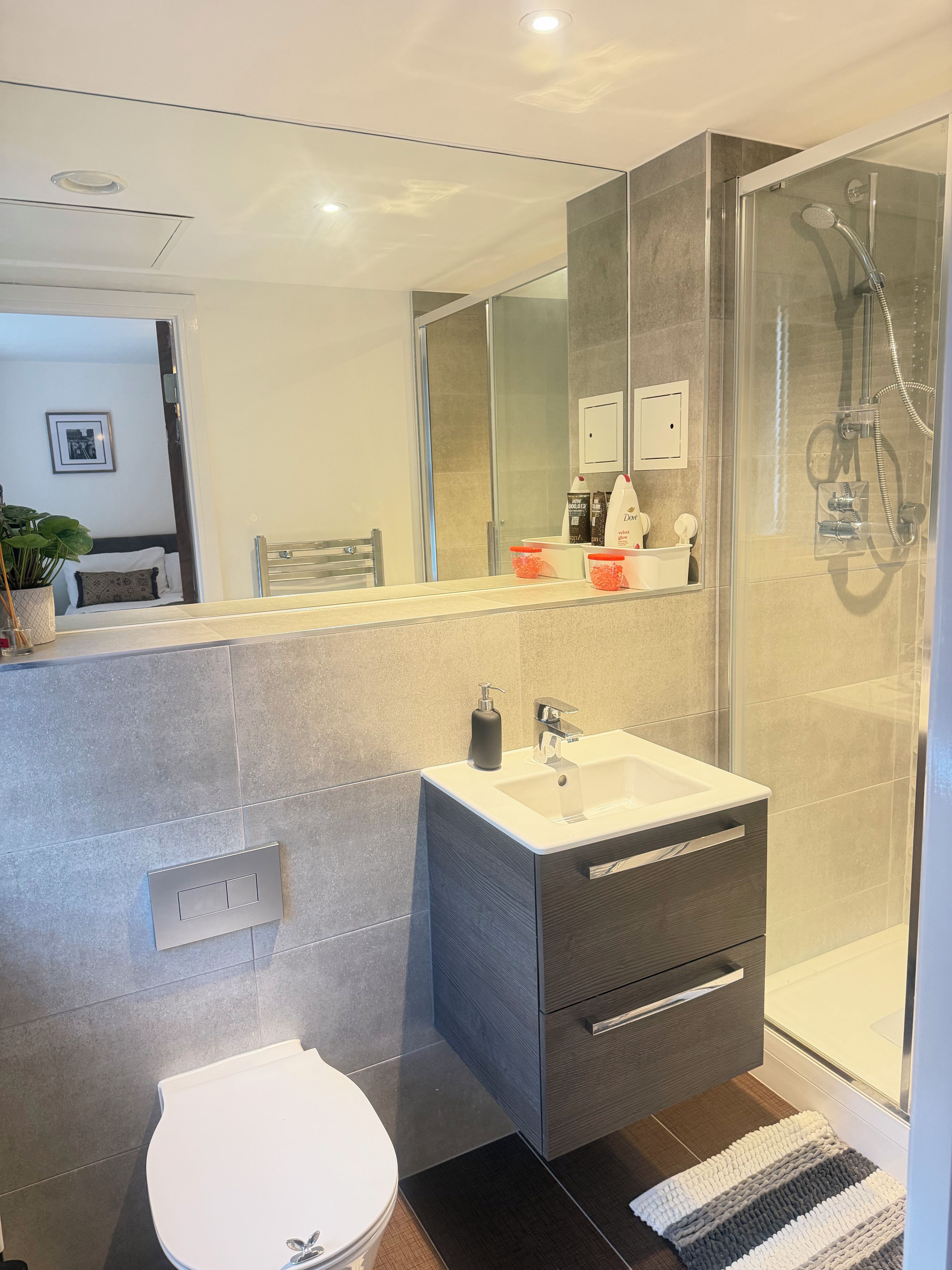 A modern bathroom with a glass shower enclosure, a white sink, and a toilet.