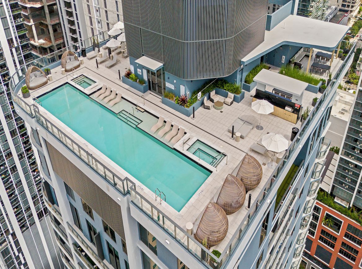 A rooftop pool with lounge seating and a bar area.