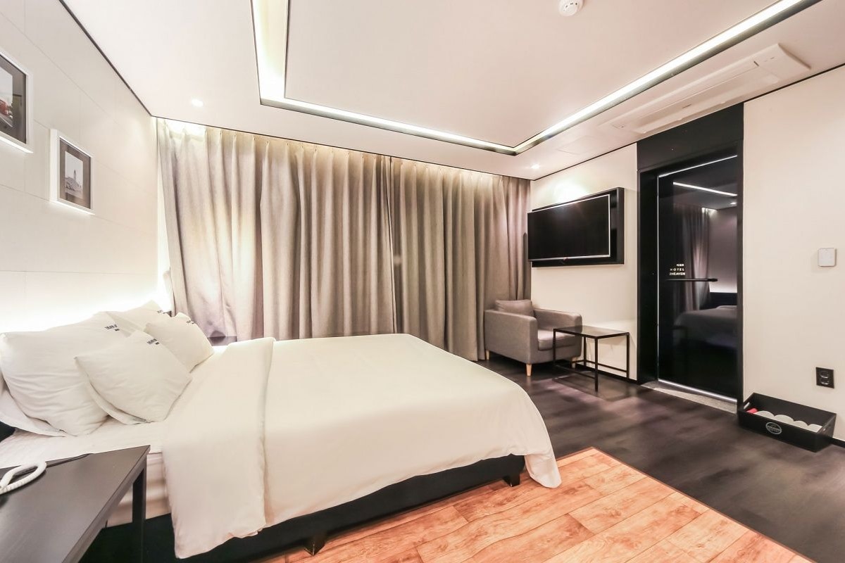 Una habitación de hotel moderna con una cama grande, un escritorio y un televisor.