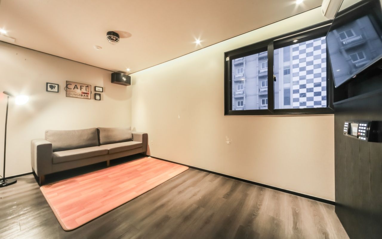 Una sala de estar moderna con un sofá, una mesa de centro, una lámpara de pie y una ventana con vistas a edificios.